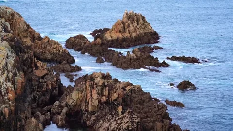 Small waves of the Atlantic Ocean crash against the rocks of the coast Stock Footage 303245867