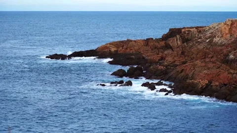 Small waves of the Atlantic Ocean crash against the rocky shore Stock Footage 303246059