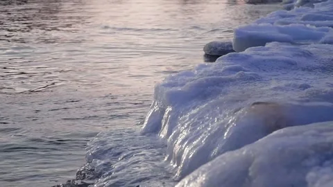 Small waves of the Baltic Sea pour over the icy shore in winter Stock Footage 268724201