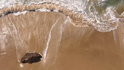 Small waves from blue water breaking on single rock at beautiful clean beach Stock Footage 129738078