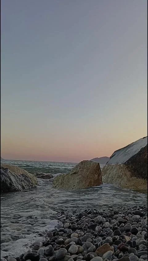 Small waves break gently against sunlit coastal rocks. Stock Footage 338203798