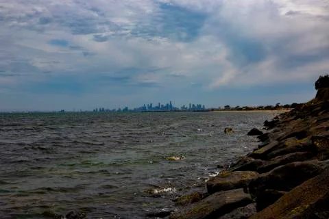 Small Waves Break on Rocks with Melbourne City Skyline in Background Stock Photos