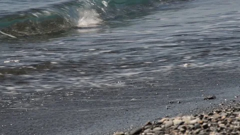 Small waves break on the shore of the sea, moving small stones Stock Footage 88209973