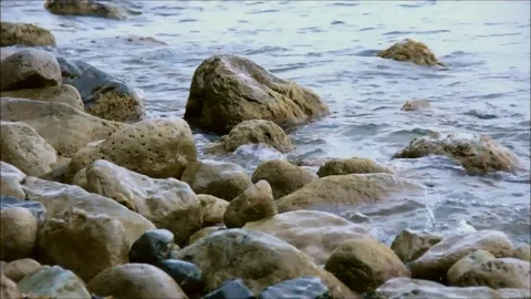 Small waves breaking against rocks Stock Footage 77862608