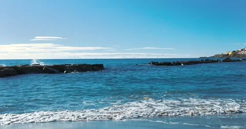 Small waves breaking on the reefs in the Italian sea next to a small city Stock Footage 240469612