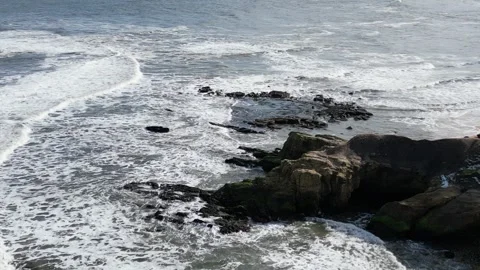 Small waves breaking on seashore rocks Stockbeeldmateriaal 253340480