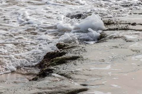 Small waves breaking on some rocks on the beach Stock Photos