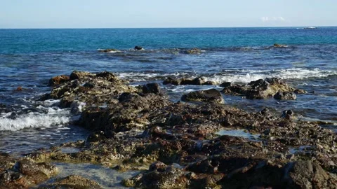 Small waves brushing into rocks on a calm beach Stock Footage 142962131