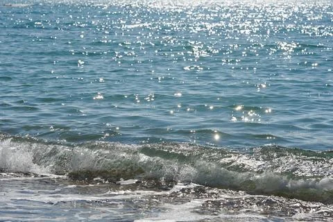 Small waves calmly roll over the sandy coastline. Reflection of the sun's rays Foto stock