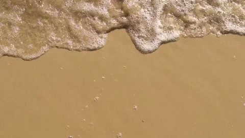 Small waves with clean transparent water roll onto coastal sandy surface. Stock Footage 285023962