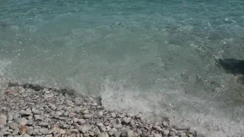 Small waves in clear blue sea. Pebble stone beach. Video stock 316920493