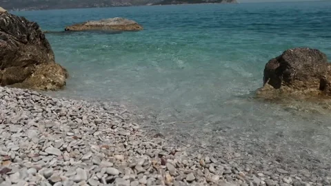 Small waves in clear blue sea. Pebble stone beach. Stock Footage 316920495