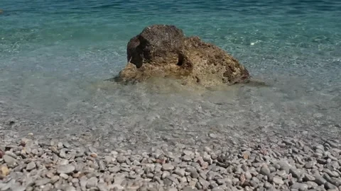 Small waves in clear blue sea. Pebble stone beach. Stock Footage 316920499