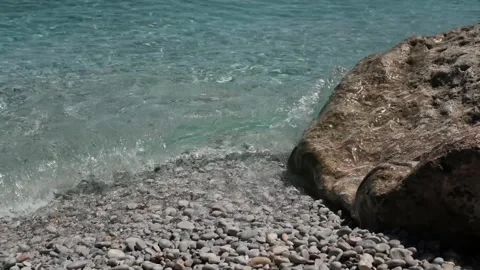 Small waves in clear blue sea. Pebble stone beach. Stock Footage 316920511