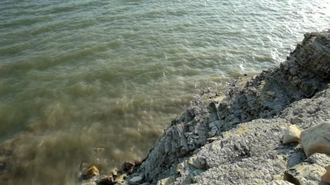 Small waves crashing against the rock wall at the edge of the lake 動画素材 290287424