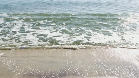 Small waves crashing on the beach during a bright summer day Stock Footage 76591421