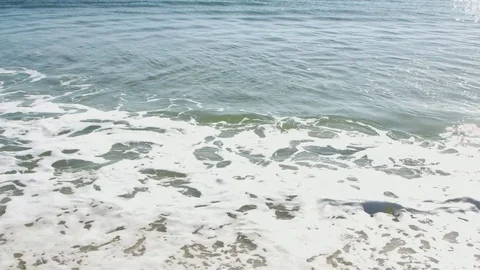 Small waves crashing on the beach during a bright summer day Stock Footage 76591437