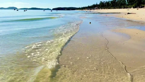 Small waves crashing on white sand shimmering under golden sun at Hong Van Stock Footage 326479121