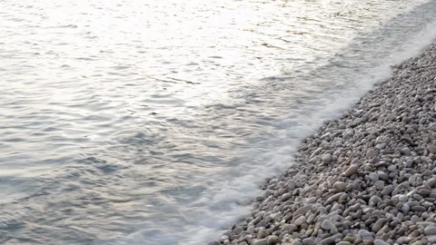 Small waves crushing at sunset on a pebble beach in Croatia Stock Footage