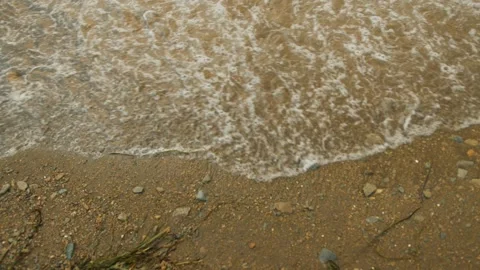 Small waves with foam run onto the sandy shore and washed out small pebbles 스톡 동영상 318671583