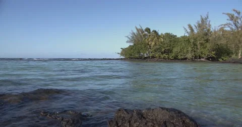 Small waves gently lap volcanic rocks in a Hawaiian bay Stock Footage 137214736
