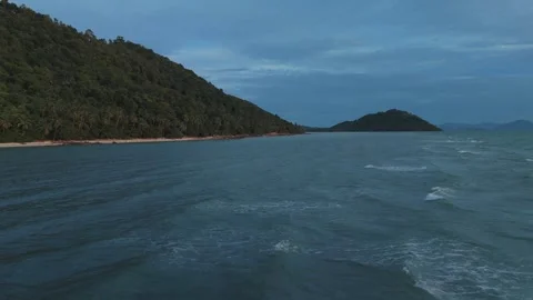 Small waves gently rolling toward tropical island coastline during sunset Stock Footage 312745941