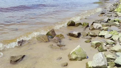 Small waves hit rocks on a beach Stock Footage 169047913
