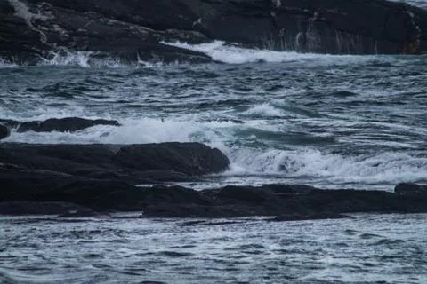 Small waves hitting black rocks from the tlantic ocean Stock Photos