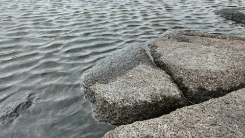 Small waves hitting grey rocky shore Stock Footage 192873627