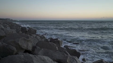 Small waves hitting rocky shore sunrise Stock Footage 98742797