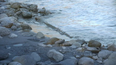 Small waves lapping on the riverside with rocks and sand in the cool shade Stock Footage 170114447