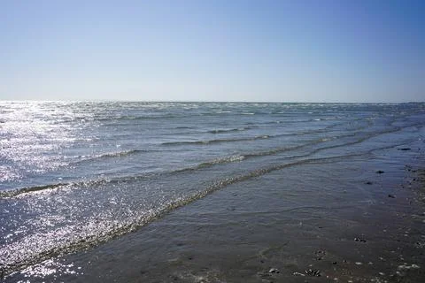 Small waves lapping up on a sandy beach Stock Photos