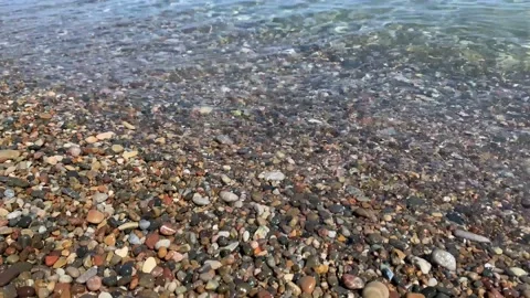 Small Waves on pebble beach. Clear water waves flowing over pebble beach shore Vídeo Stock 207451306