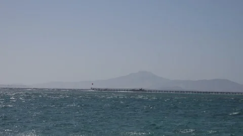 Small Waves in the Red Sea. A Long Pier and a High Mountain In the Distance Stock Footage 117578784