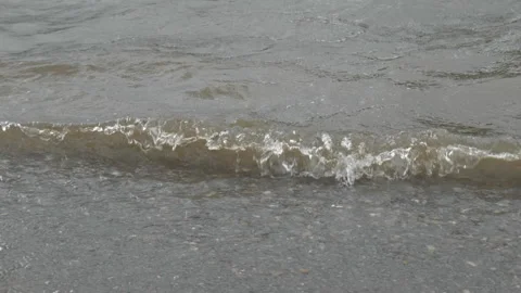 Small waves ripple and foam gently at the shore of a lake. Stock Footage 313770546
