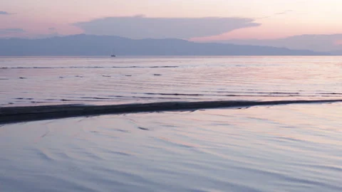 Small waves ripple on shallow beach of lake at sunset. 4K Stock Footage 231544996