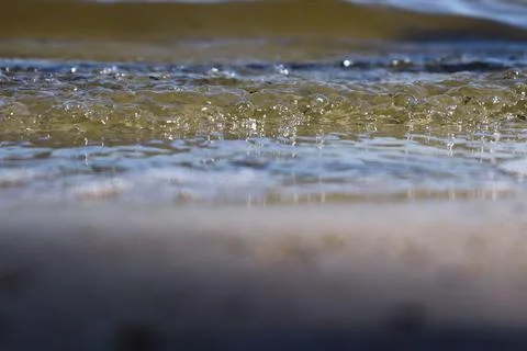 Small waves of the river close-up with sun glare. Stock Photos
