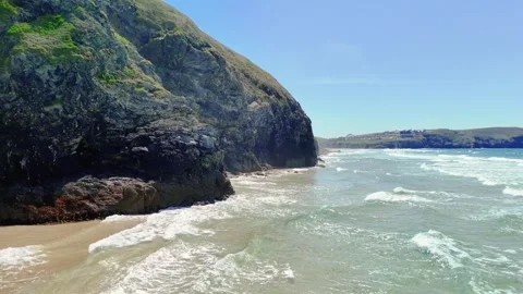 Small Waves Roll Across Beach and Crash on Rocky Cliffside,  Cornwall. Stock Footage 310135610
