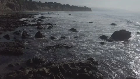 Small waves roll over the rocks on the California coast at sunset Video stock 167552549