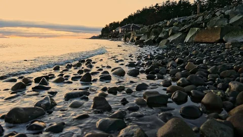 Small waves rolling over smooth rocks along coast with home in distance Stock Footage 129001509