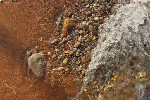 Small Waves Rolling into Sandy Beach Dotted with Colorful Pebbles, Rocks, and Stock Photos