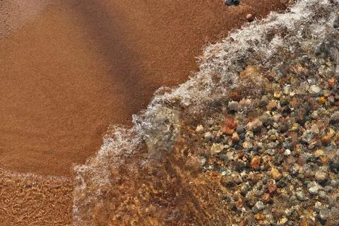 Small Waves Rolling into Sandy Beach Dotted with Colorful Pebbles, Rocks, and Stock Photos