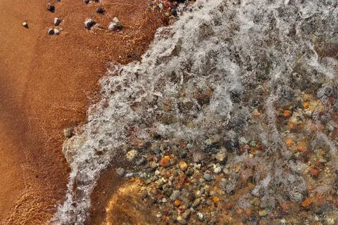 Small Waves Rolling into Sandy Beach Dotted with Colorful Pebbles, Rocks, and Stock Photos