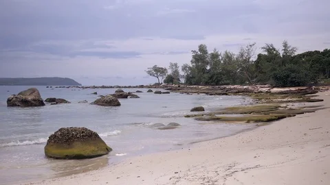 Small waves rolling on a tropical white sand beach scattered with boulders Stock Footage 81830936