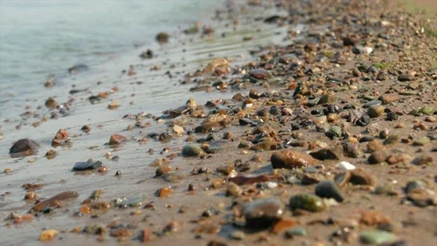 Small waves run over the sandy seashore with small pebbles, close-up Stock Footage 139850145