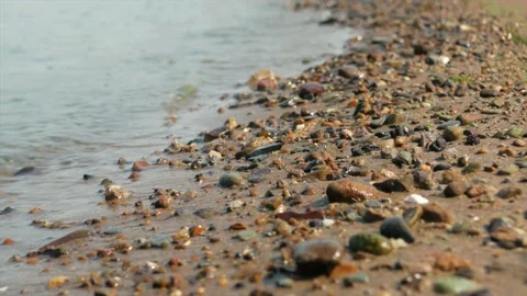 Small waves run over the sandy seashore with small pebbles, close-up Stock Footage 139850147