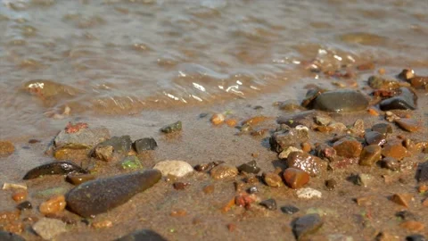 Small waves run over the sandy seashore with small pebbles, close-up Stock Footage 139850165