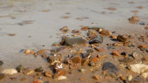 Small waves run over the sandy seashore with small pebbles, close-up Stock Footage 139850168
