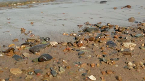 Small waves run over the sandy seashore with small pebbles, close-up Stock Footage 139850172