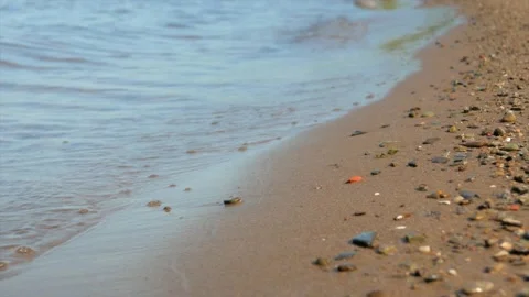 Small waves run over the sandy seashore with small pebbles, close-up Stock Footage 139850253
